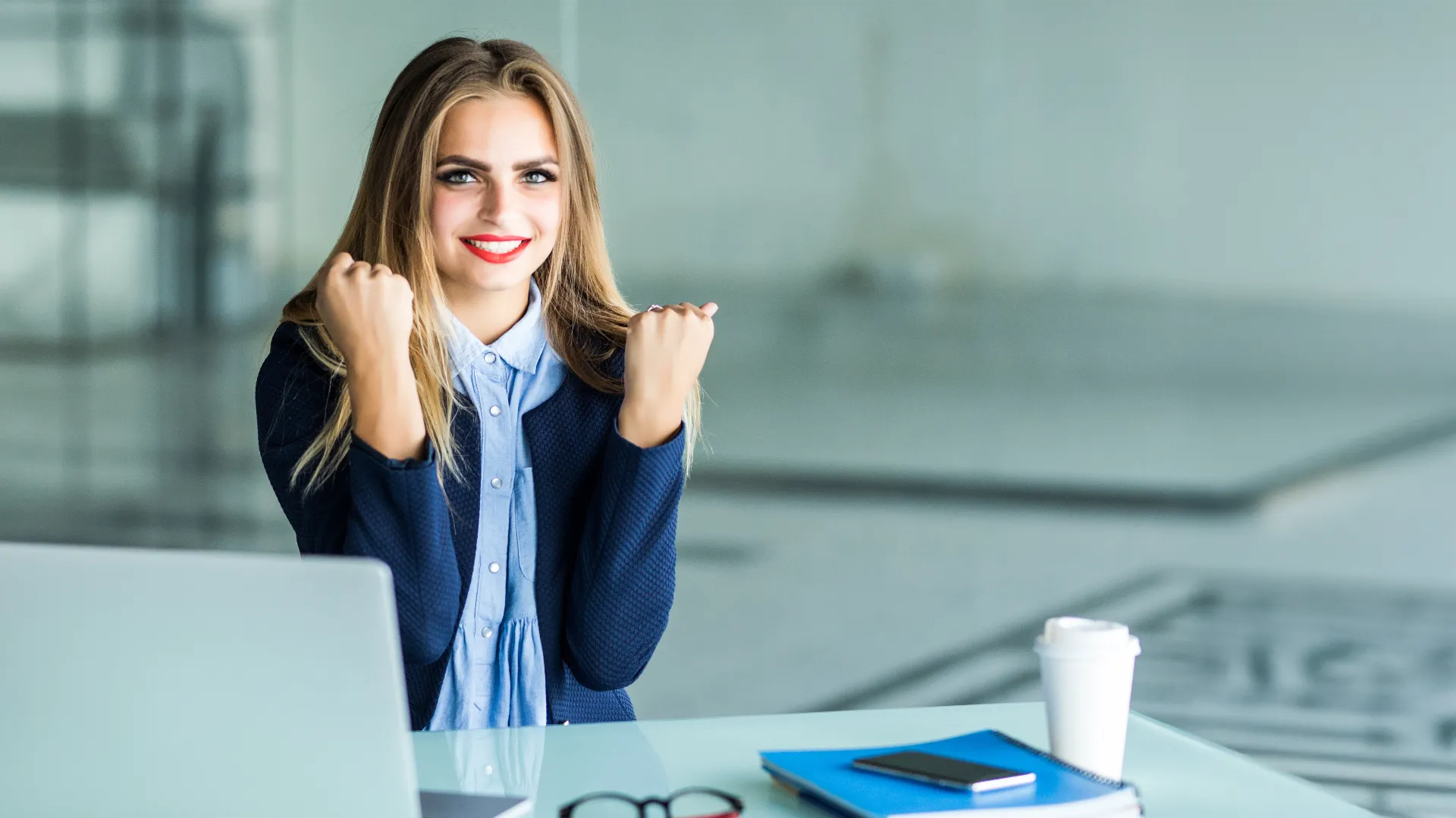 excited businesswoman winning after achievement reading smart phone sitting desktop office bg